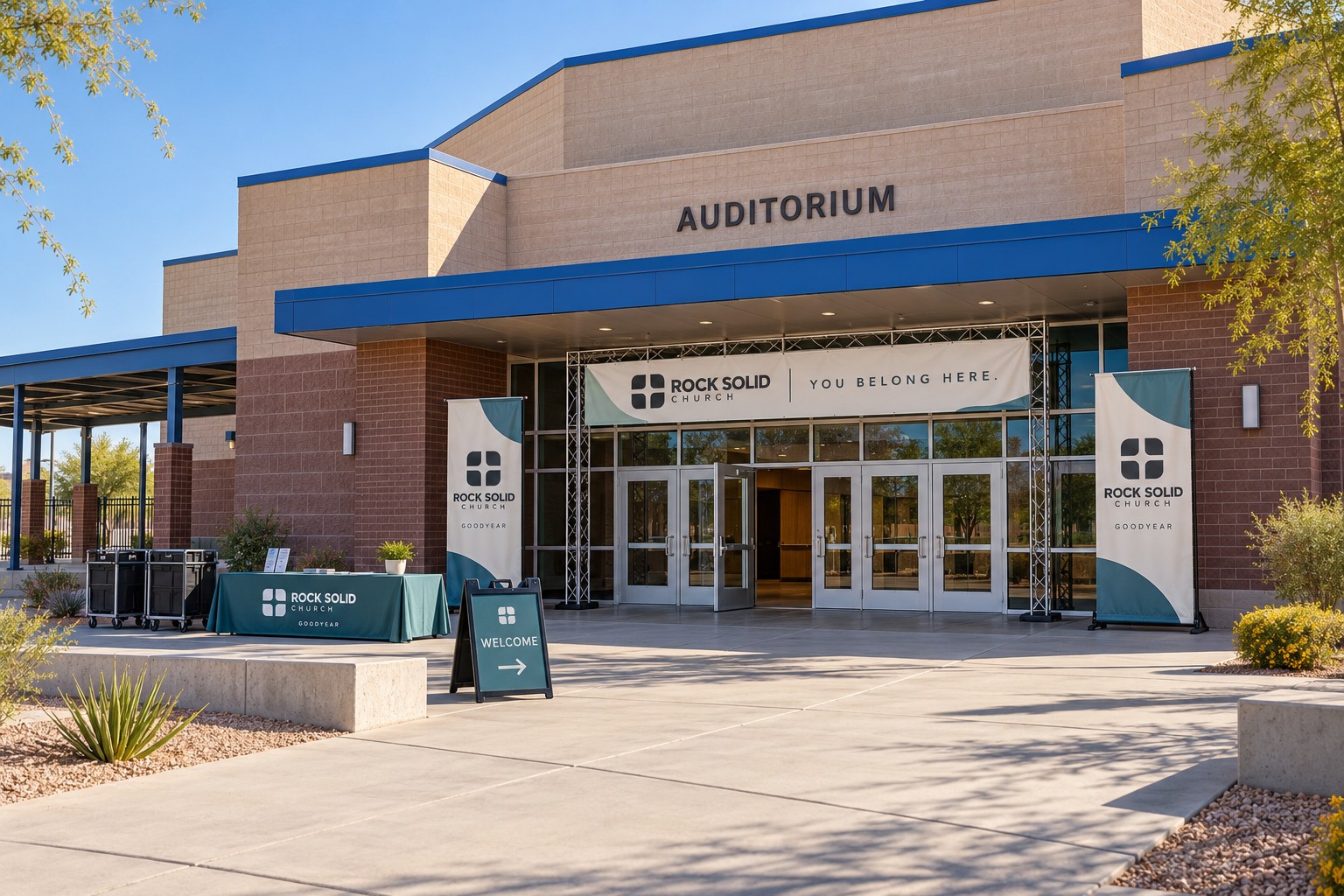 Goodyear's high school auditorium, with portable Rock Solid Church banners, a welcome table, and Sunday setup carts.